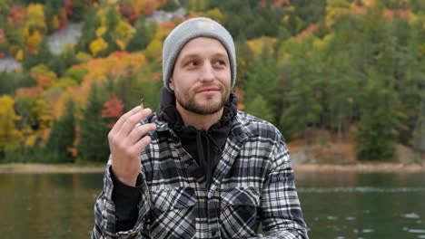 handsome young man smiles and smokes a weed joint in autumn, handheld