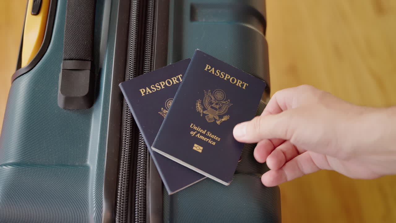 Mano che appoggia due passaporti degli Stati Uniti su una valigia per un viaggio