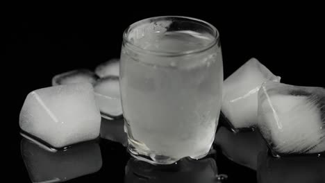 Pour-vodka-into-icy-glass-with-ice-cubes-placed-on-a-black-background