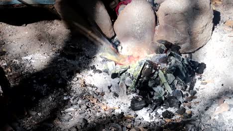 Hombre-De-La-Tribu-Datoga-Quitando-Un-Recipiente-Con-Cobre-Fundido-Del-Calor-Para-Verterlo-En-Otro