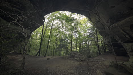 Huge-natural-stone-arch-formation-towers-over-quiet-peaceful-forest,-4K