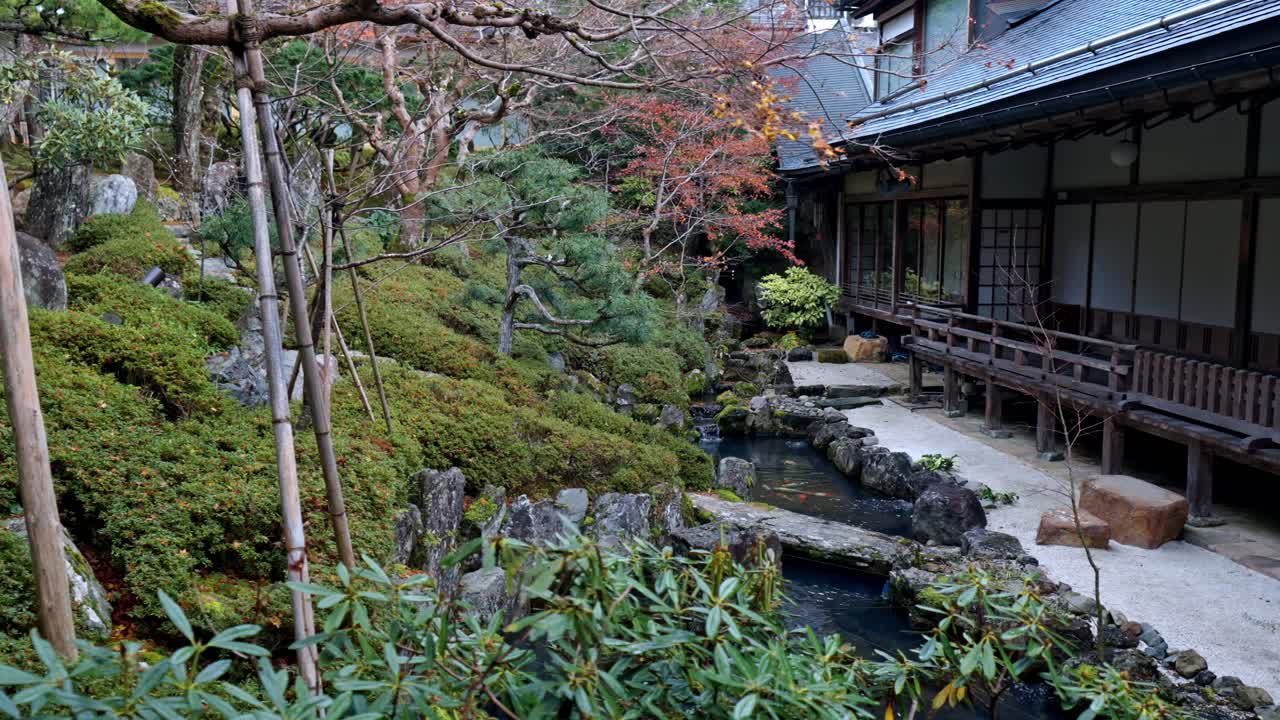 Ryokan temple garden in Koyasan adorned with vibrant autumn foliage. Lush green garden, a koi pond with colorful fish gracefully swimming, and the timeless beauty of traditional Japanese design.