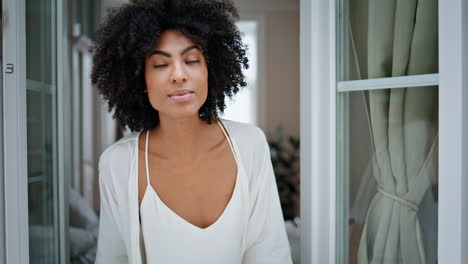 curious lady peeping window at weekend indoors. african woman looking street