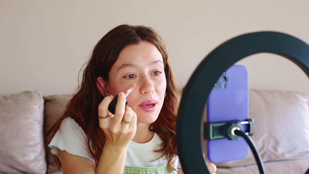 Woman filming makeup tutorial with ring light and phone