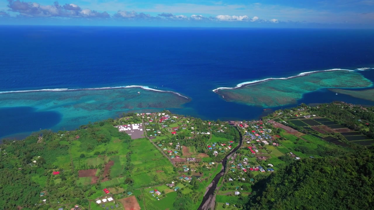 Vista aerea di Teahupo'o, villaggio di Tahiti, Polinesia Francese, in una mattina di sole. Fine della strada, edifici del quartiere ripresi da drone, onda di Teahupo'o, laguna per il surf, barriera corallina di Passe Havea, fiume Vaiau. Panoramica in avanti verso l'alto.