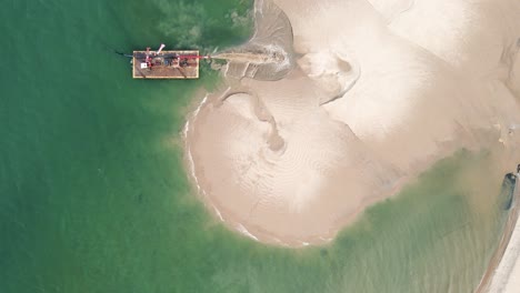 rising over lake michigan as a barge pumps sand forward