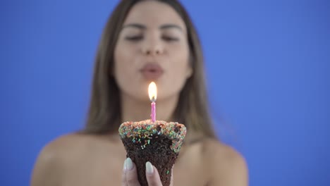 woman blowing out candle on birthday cupcake