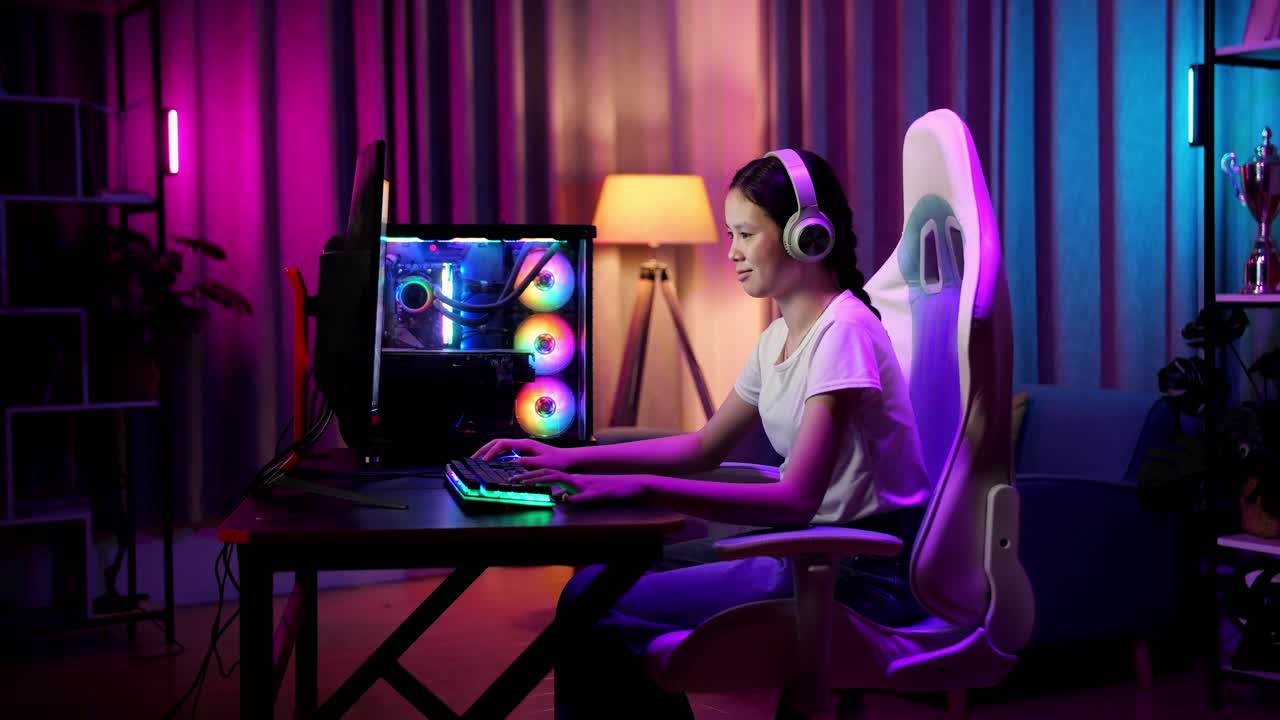 una adolescente asiática emocionada jugando videojuegos en la computadora