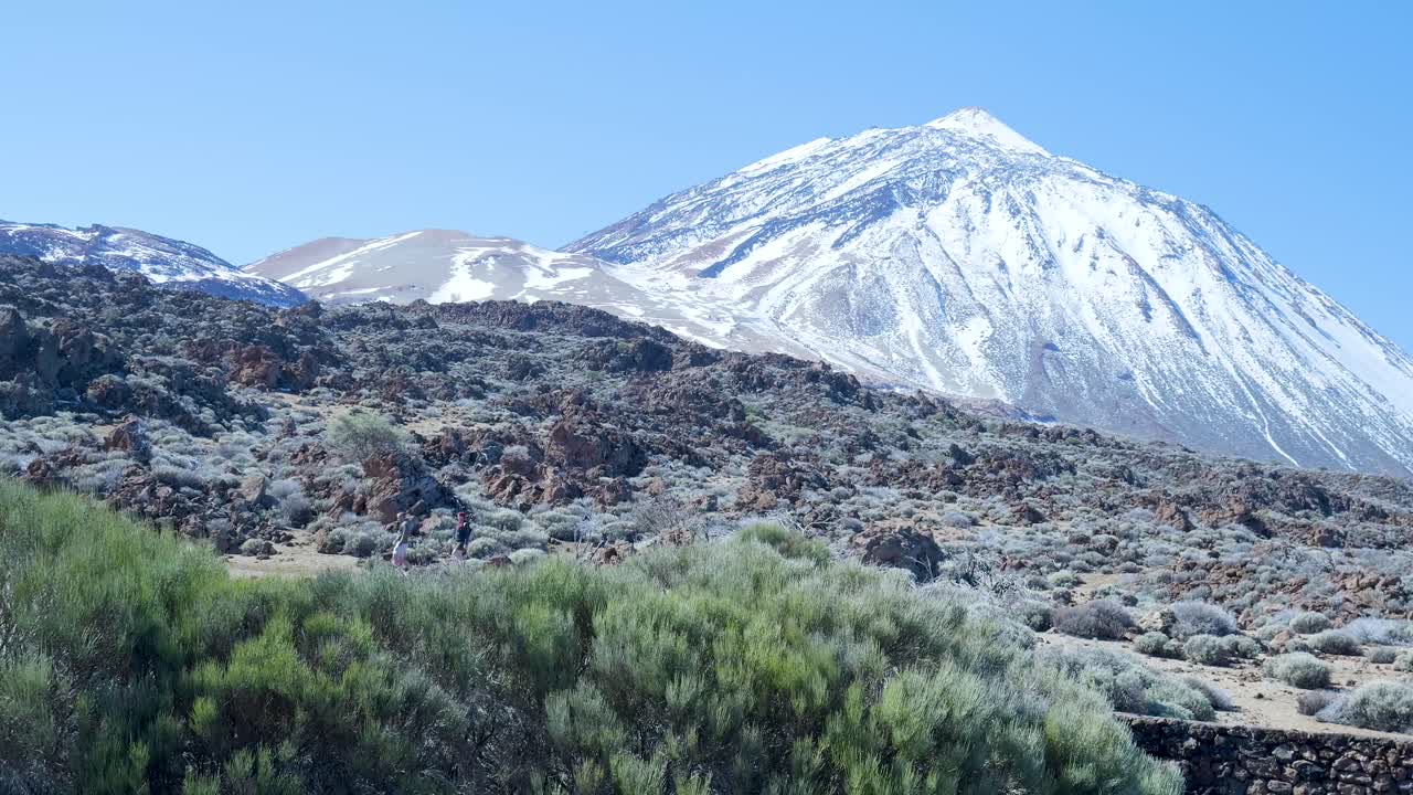 Paesaggio montano innevato con terreno vulcanico ed escursionisti
