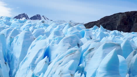 glaciar derretido iluminado por el sol azul, grietas profundas, montañas distantes