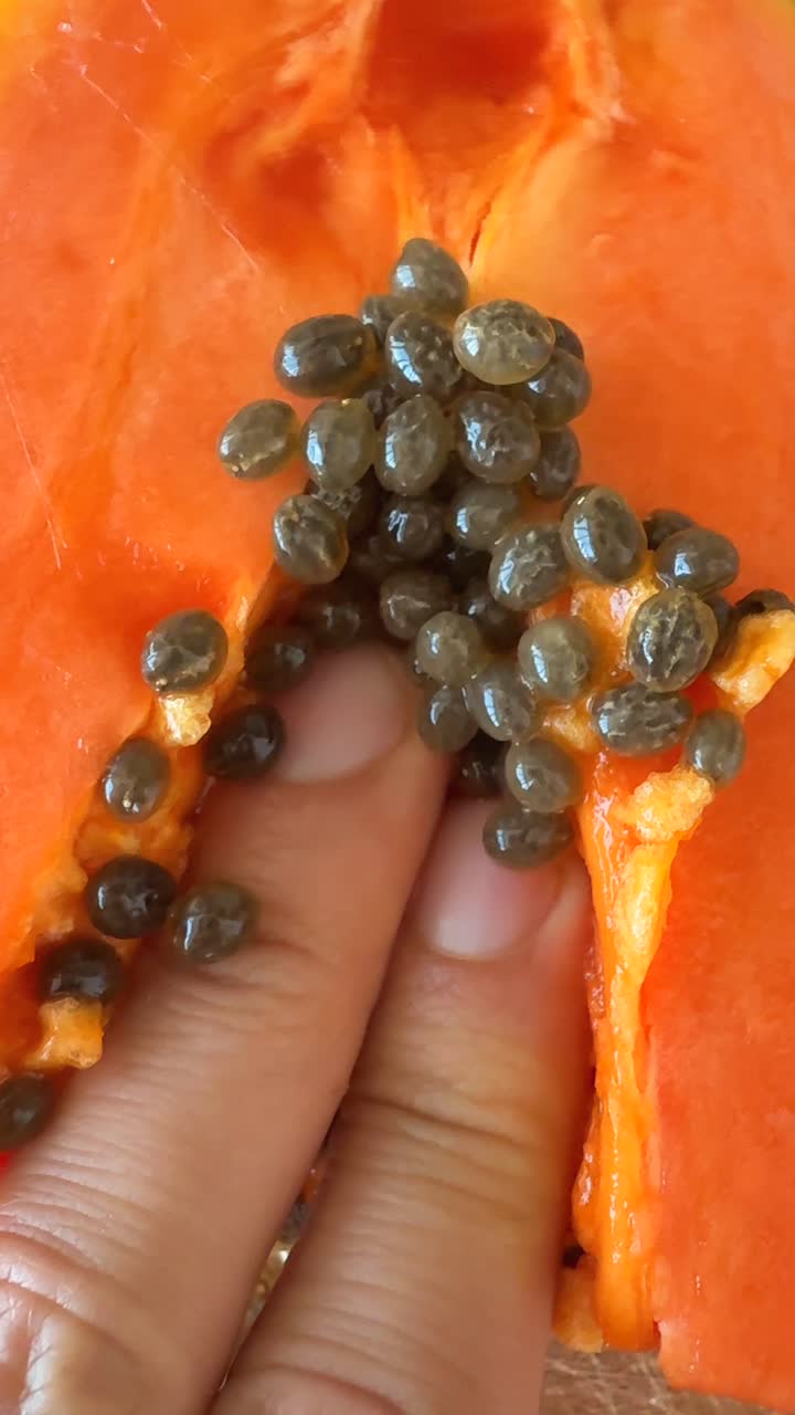 Close-up of Papaya with Seeds and a Hand