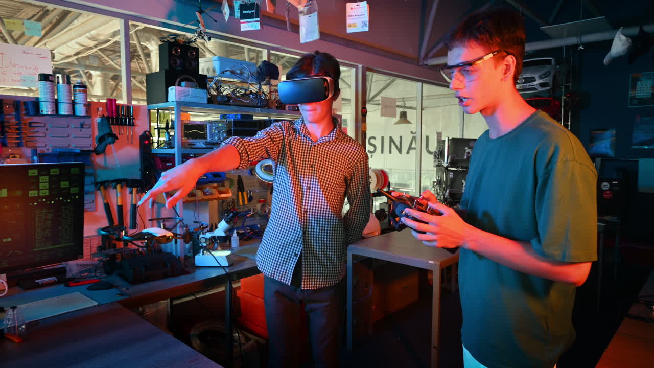 Teens doing experiments in robotics in a laboratory. Boy in protective glasses and guy in VR headset controlling a flying drone using controller and hand. Red and blue illumination
