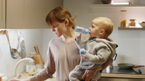 mother giving bottle of water to baby