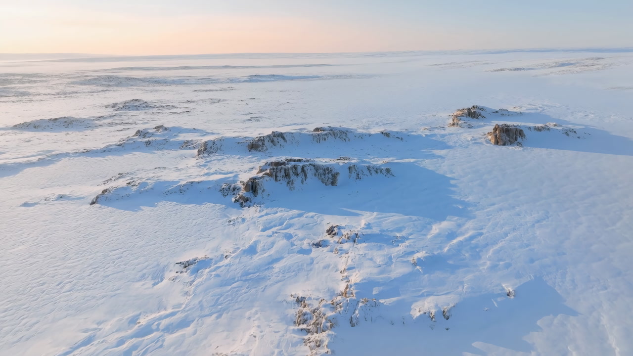 Aerial Arctic Snow Landscape At Sunrise, Soft Pastel Sky, Frozen Rock Outcrops And Vast Ice Expanse, Long Blue