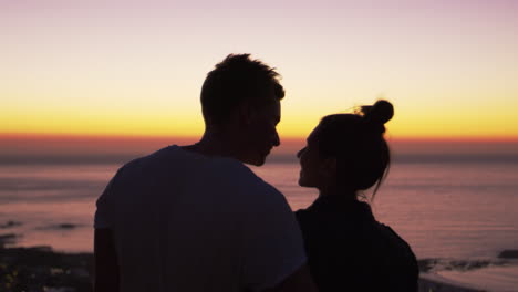 pareja besándose junto al mar al atardecer, silueta