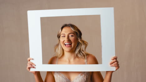 studio shot of confident natural woman in underwear making funny faces in picture frame