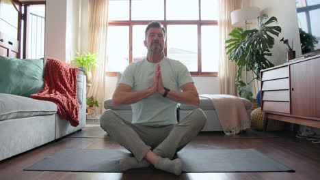 senior man meditating on yoga mat at home, finding inner peace