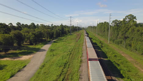 Aerial view of cargo train standing in forest near city