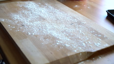 man's hands sifting flour on a wooden board for baking