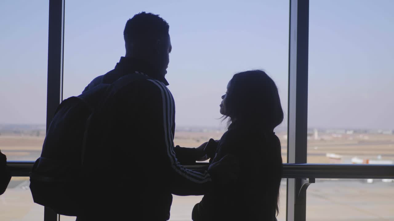 Man caresses girlfriend on top of a tower with panoramic view of a city