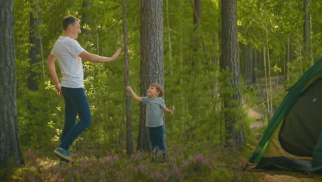 Father-and-son-beat-five-after-successfully-assembling-a-tent-in-the-woods.-Praise-and-clapping-father-and-son