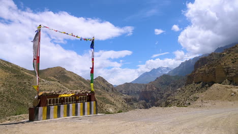 Die-Buddhistische-Flagge-Weht-Im-Wind-Zusammen-Mit-Gebetsmühlen-Und-Wunderschönen-Bergen-Und-Hügeln-Im-Mustang-Nepal