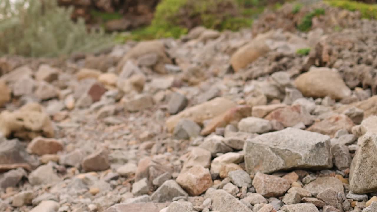 Un plano detallado en ángulo bajo de piedras erosionadas y guijarros en una costa escarpada