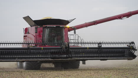 combine harvester gathering soybeans in a farm field and lifting header