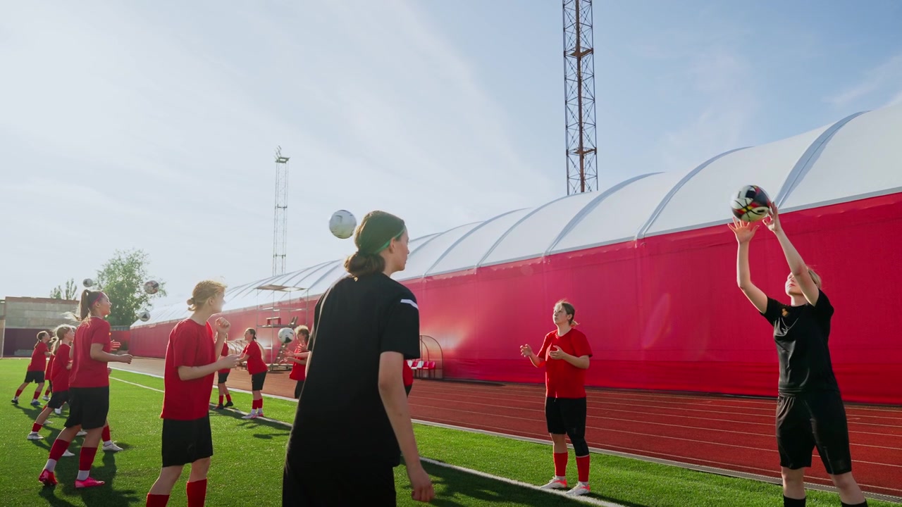 Unga kvinnliga fotbollsspelare tränar inkast på utomhusplan.