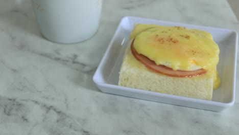 cured ham, egg and bread and cup of tea on table