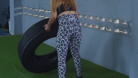 bodybuilder flipping tires in sports wear at a gym