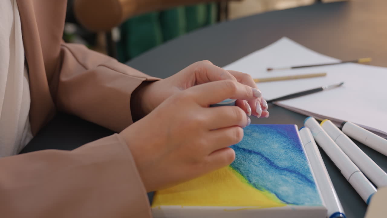Una artista experta perfecciona un paisaje marino, una artista precisa utiliza un pincel fino para destacar los detalles de la costa, una mujer concentrada emplea trazos delicados para realzar los sutiles rasgos del paisaje costero.