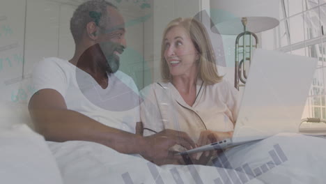 animation of statistical data processing over happy biracial couple using laptop in the bed at home