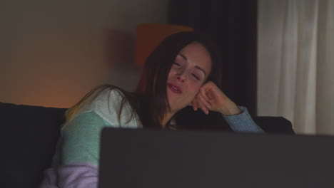 Smiling-Woman-Sitting-On-Sofa-At-Home-At-Night-Streaming-Or-Watching-Movie-Or-Show-On-Laptop-2