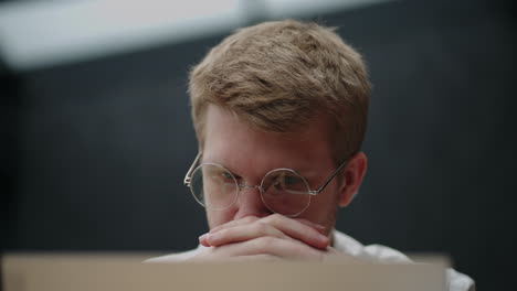 retrato de un hombre cansado y pensativo mirando la pantalla de una computadora portátil con gafas. un hombre de lluvia de ideas. resolución de problemas. pensar y trabajar