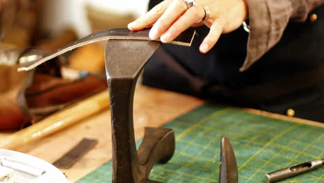 mid-section of craftswoman nailing leather