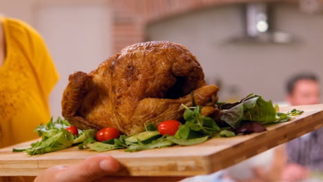 Feminine-hands-bringing-a-chopping-board-with-the-chicken-on-it