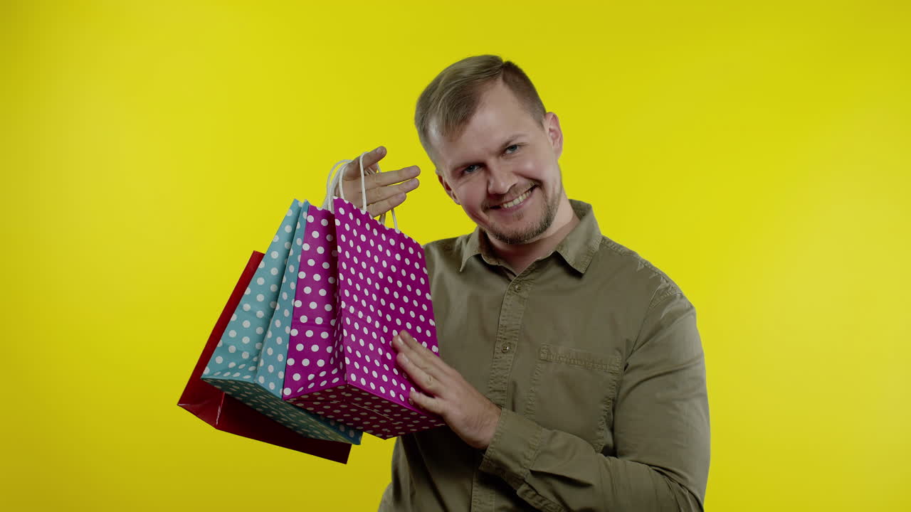 hombre alegre mostrando la inscripción de black friday de las bolsas de compras, sonriendo satisfecho con los precios bajos