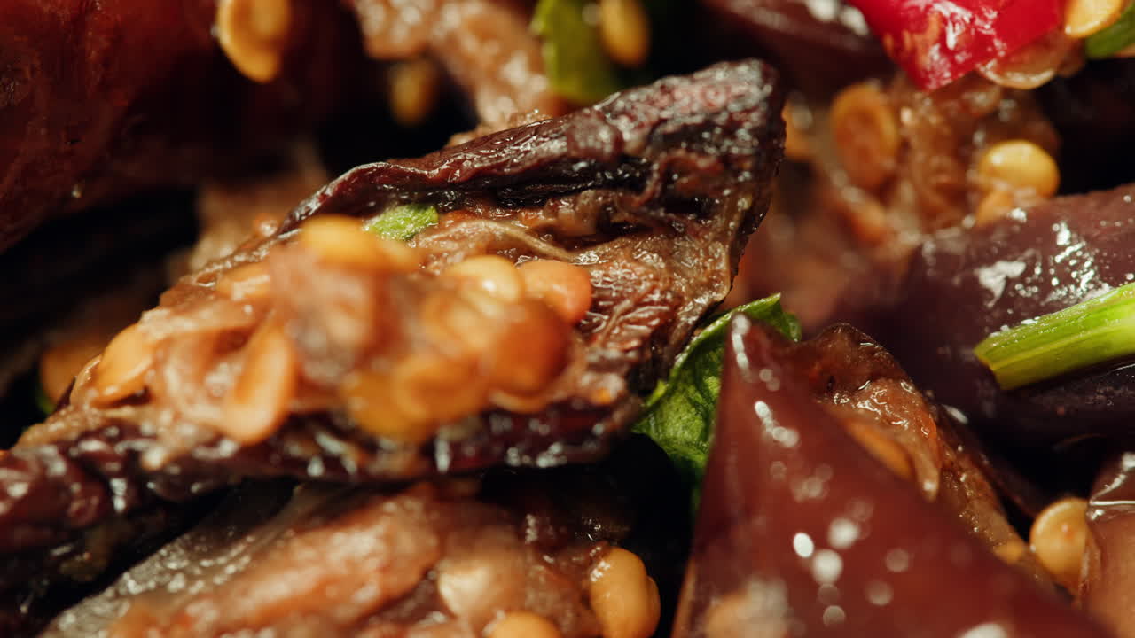 Close-up of fermented eggplants with red sweet pepper and mustard on plate. Preservation of vegetables in glass jars. Fermentation preserved aubergine with hot chilli peppers and greens.