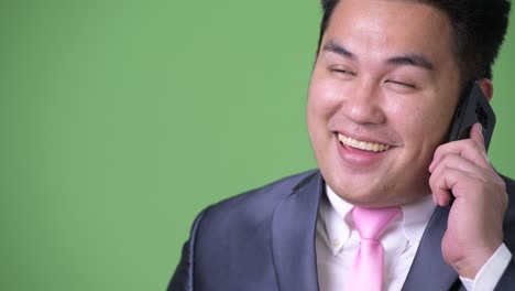 초록색 배경에 젊은 잘생긴 과체중 아시아 사업가