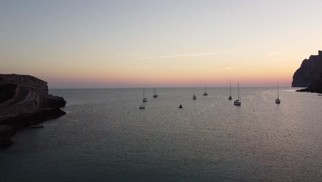 amanecer en la costa con veleros en el mar