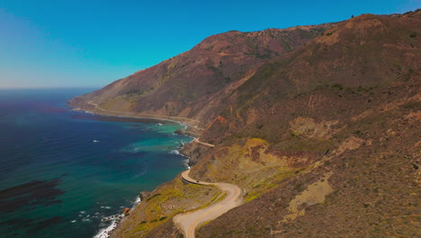 sloping mountains with ocean waters at their foot. dangerous highway in the rocks along the coastline. aerial perspective.