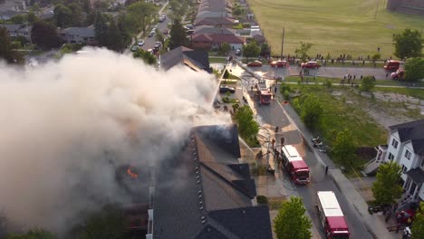 Atemberaubender-Blick-Von-Oben-Auf-Ein-In-Flammen-Stehendes-Haus-Und-Feuerwehrleute-Mit-Löschfahrzeugen,-Die-Tonnen-Wasser-Werfen