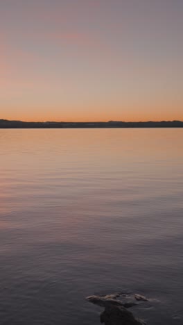 tranquil lake at sunset or sunrise with distant mountains
