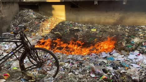 landfill full of rubbish burning with orange flames in dhaka