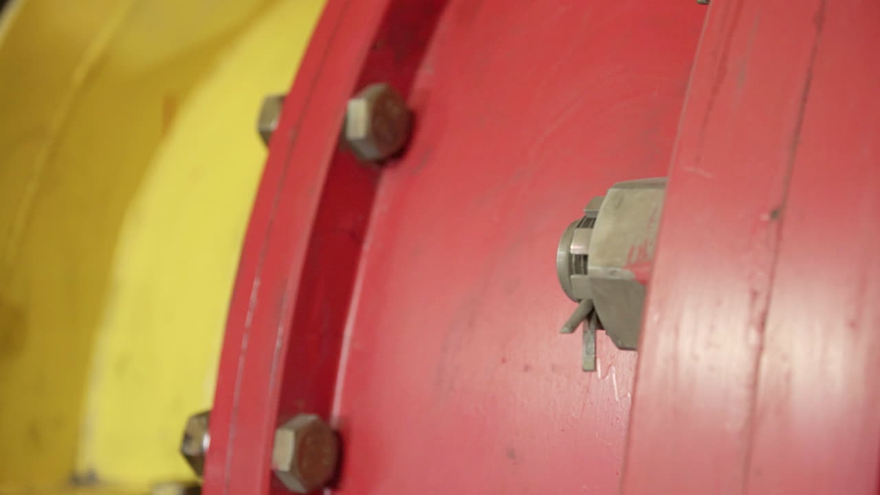 primer plano de un accesorio de tubería rojo y amarillo con pernos y tuercas