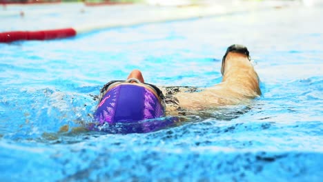 Zeitlupenaufnahme-Einer-Frau,-Die-Auf-Dem-Rücken-In-Einem-Innenpool-Schwimmt