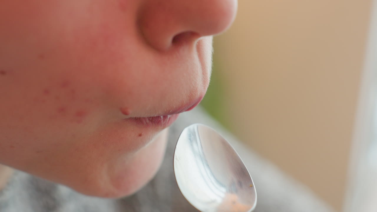 Student scooping beverage with spoon and savoring taste in warm cafe environment gentle focus on mouth and drink moment of enjoyment reflected in facial expression relaxing break during study session