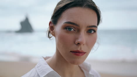 Portrait-calm-woman-ocean-waves-at-cloudy-day.-Calm-model-posing-beach-close-up.