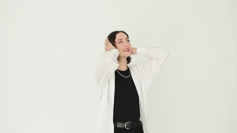 young woman posing against a white background with hands on her head